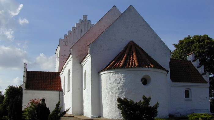 Hvidt kirke med spånt tak og smukke detaljer.