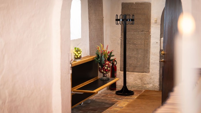 Lille entre med tøjstativ, blomster og bænk.