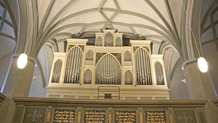 Große Kirchenorgel mit aufwendigen Schnitzereien und zwei Leuchten