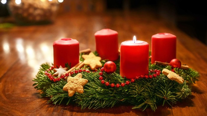 Trois bougies rouges allumées entourées de décorations de Noël sur une table en bois