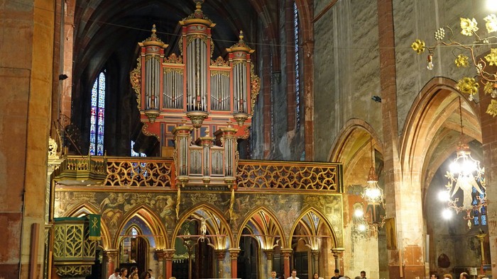 Une grande église avec un orgue orné et des vitraux colorés.