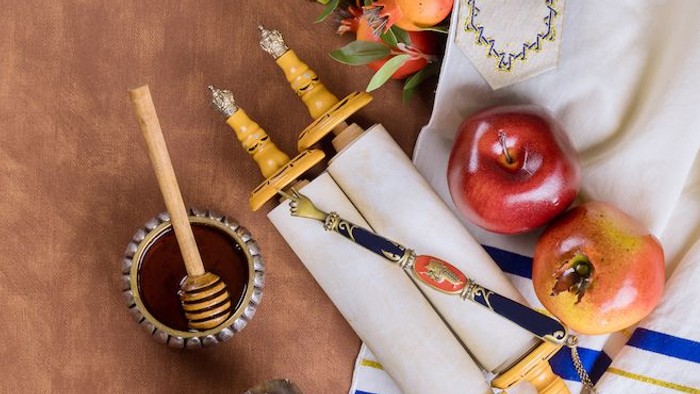Objets traditionnels de Roch Hachana, notamment des pommes, du miel et des cornes de chofar sur une nappe festive.