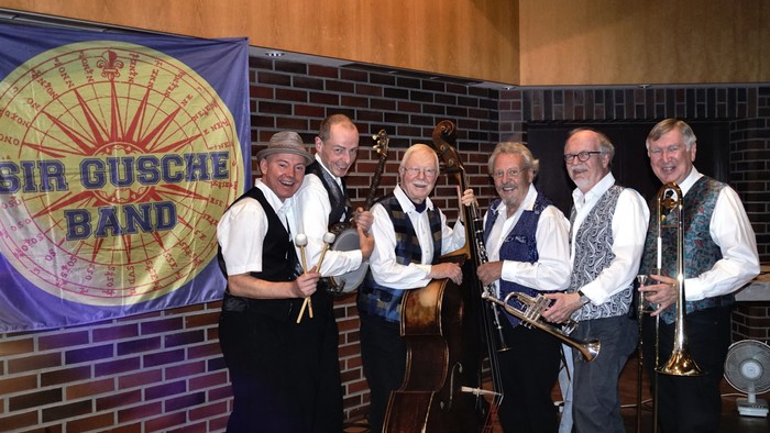 Eine Band posiert vor einem Banner mit der Aufschrift 