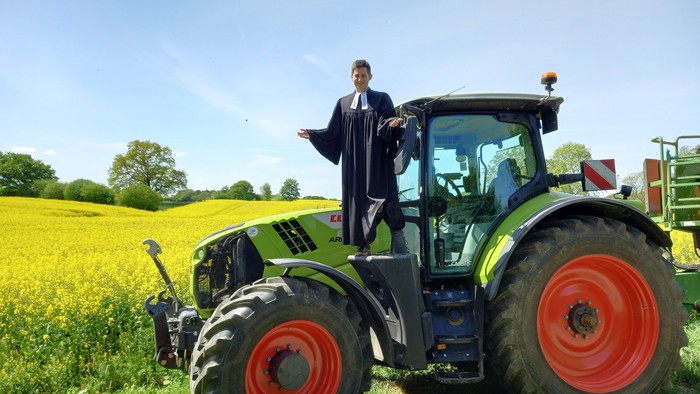 Der Pastor steht auf einem großen Trecker.