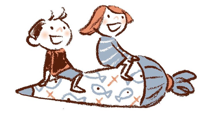 Zwei Kinder spielen auf einem Teppich mit Fischen.