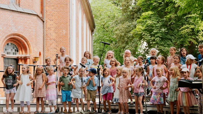 Kinderchor vor Backsteingebäude singt