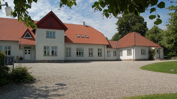 Hvidt hus med røde tage og grusbelagt indkørsel.