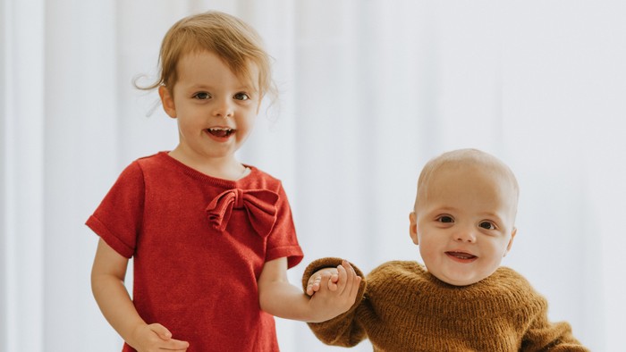 To børn danser sammen i et lys rum