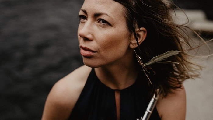 En kvinde med mørkt hår og store øreringe ser til side.