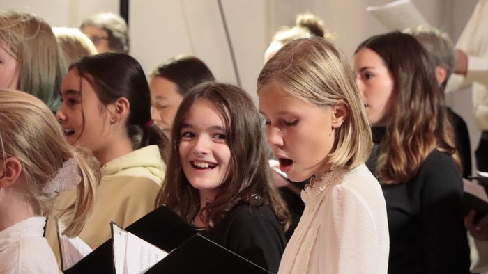 Ein Kinderchor singt aus Notenheften