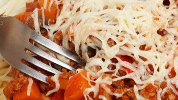 En gabel i en ret med pasta, tomatsoace og ost.