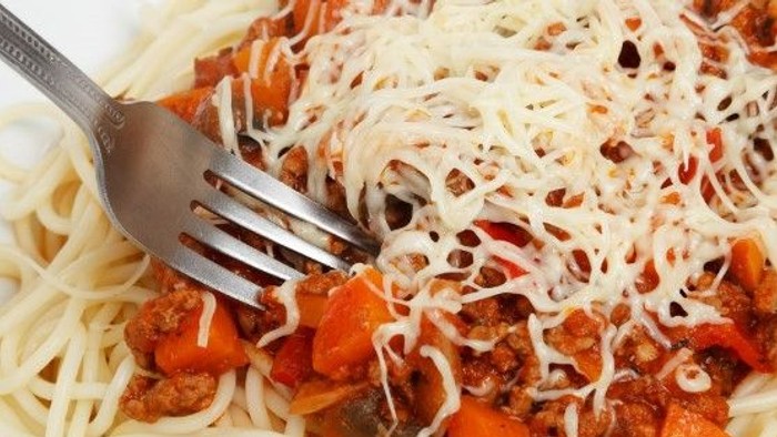 En gabel i en ret med pasta med tomat- og ostsaus.