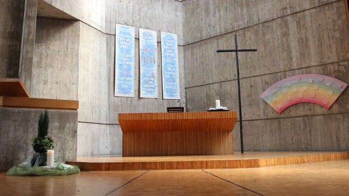 Die Kirche hat einen modernen Altar und ein farbiges Fenster.