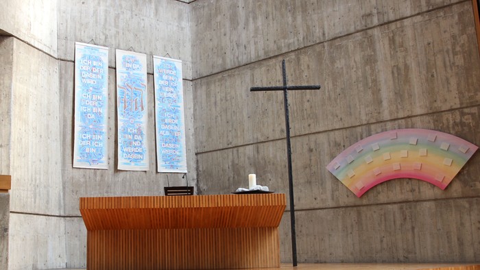 Die Kirche hat einen modernen Altar und ein farbiges Fenster.
