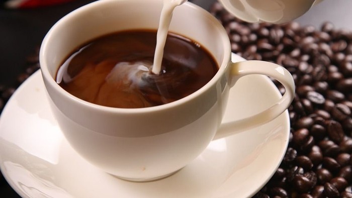 En kaffeekopp med mælk, kaffebønner og en kaffekanne