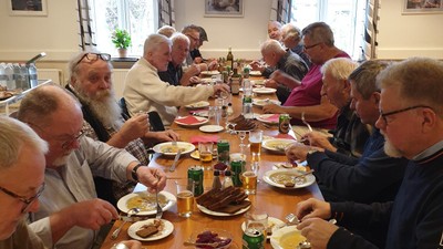 En gruppe mennesker spiser sammen ved et langt bord i et restaurant.