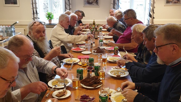 En gruppe mennesker spiser sammen ved et langt bord i et restaurant.
