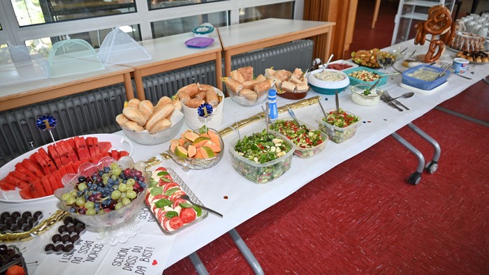 Bunter Buffettisch mit verschiedenen Broten, Salaten, Früchten, Dips und Snacks für eine Zusammenkunft.