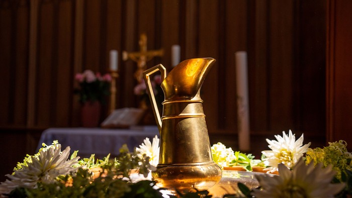 Goldener Krug, umgeben von weißen Blumen auf dem Tisch