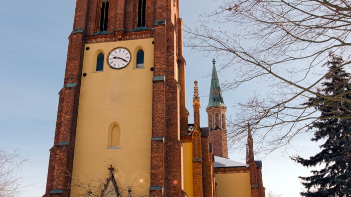 Kirche mit Uhrturm und Spitztürmen, umgeben von Schnee.