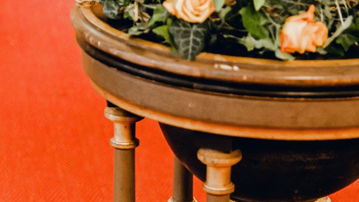 Holztisch mit Blumen und Grünpflanzen auf rotem Teppich