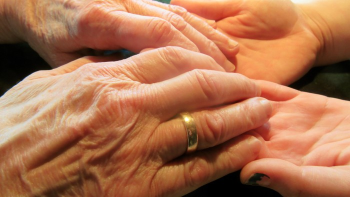 Drei Hände, die sanft auf einer Tischdecke liegen