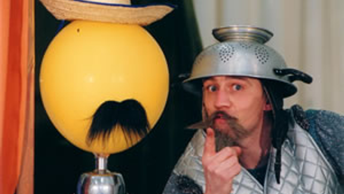 Ein Mann mit einem silbernen Helm und ein gelber Ball mit Schnurrbart und Hut.