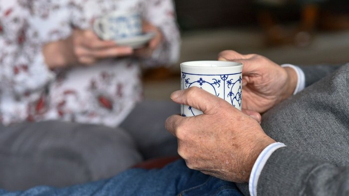 Zwei Personen trinken aus blau-weißen Tassen.