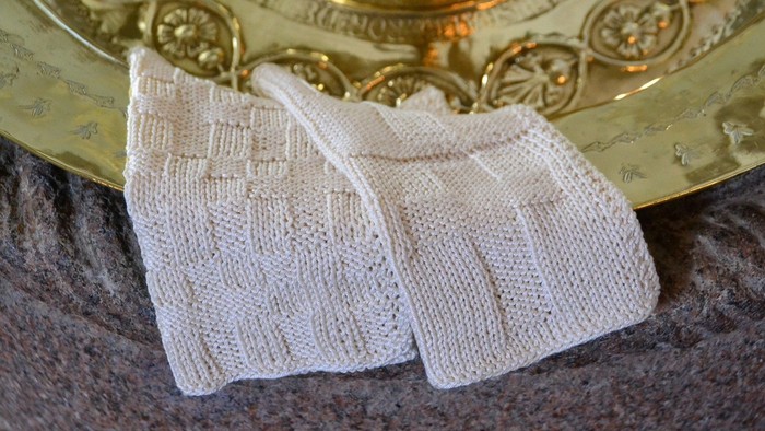 To white håndklæder ligger på en guldfarvet underliggende.