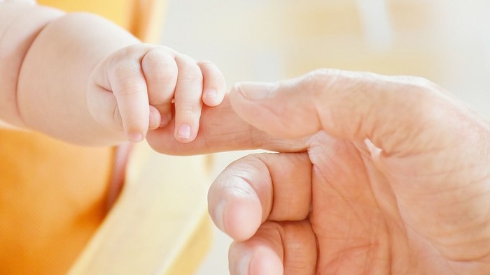 Ein Baby hält die Hand eines Erwachsenen.