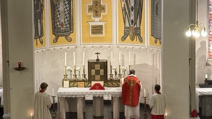 Liturgische Zeremonie im Gange an einem prächtigen Altar mit Geistlichen in liturgischen Gewändern und Kerzen.