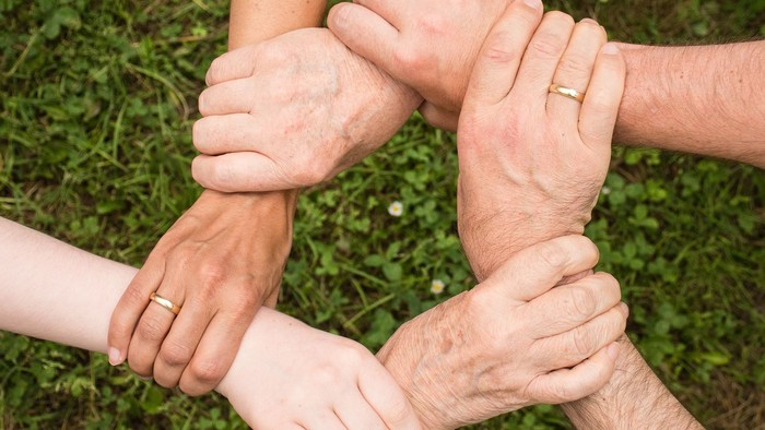 Eine Gruppe von Menschen, die sich im Kreis an den Händen halten und im Freien Einheit und Teamwork symbolisieren.