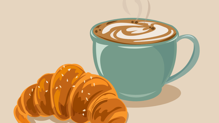 En croissant og en blå kaffekop med skumet kaffe