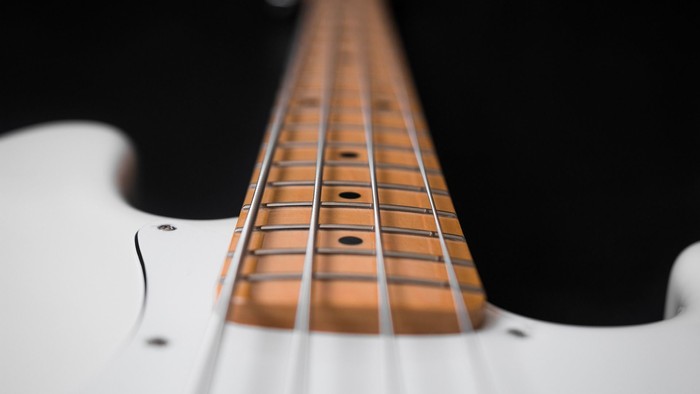 Et hvid elektrisk guitar med trusset hals og several strenge.
