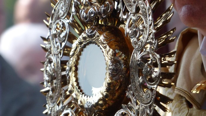 Eine goldene, verzierte Monstranz wird von einer Person gehalten
