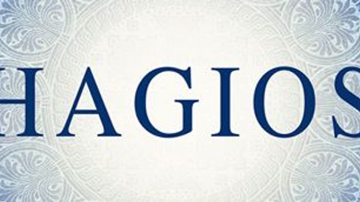 Das Bild zeigt den Namen "Hagios" in blauer Schrift auf einem weißen Hintergrund mit blauem Muster.