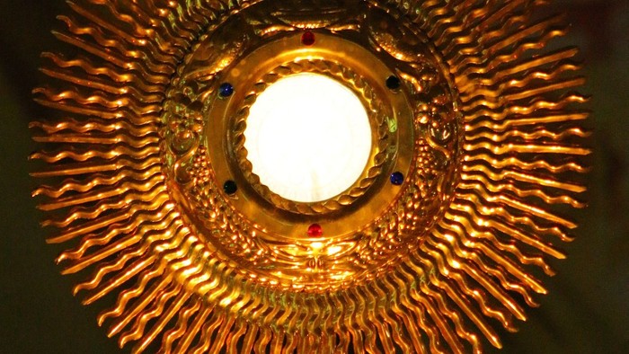 Goldener Leuchter mit Kreuz und hellen Licht.