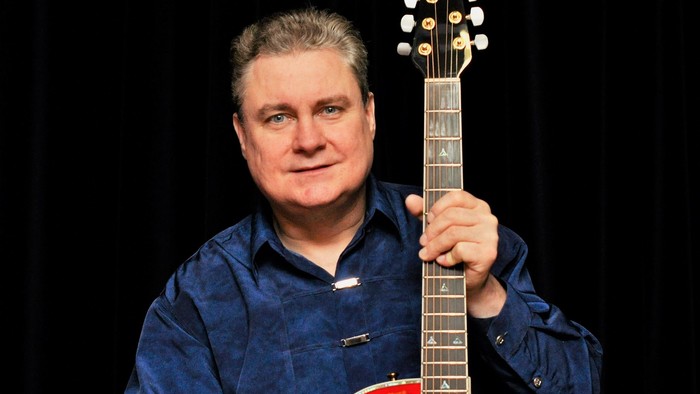 Foto von Günter Rüdiger in blauem Hemd mit roter Gitarre