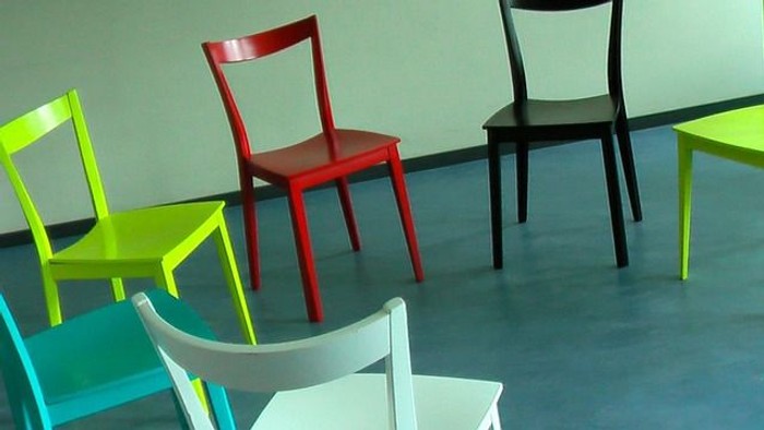 Vier farbenfrohe Stühle vor grauer Wand