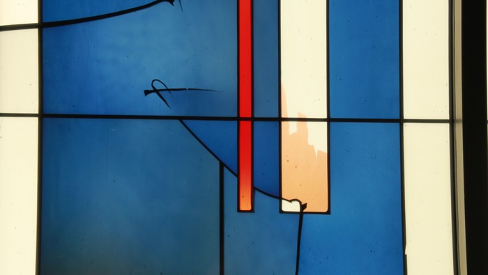 Nahaufnahme einer blauen Wand mit freiliegender Verkabelung, einem roten Rohr und einem beigen Elektrokasten.