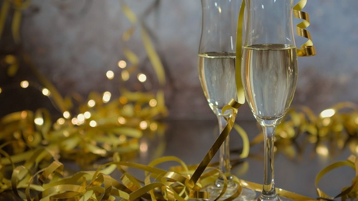 To guldglasede med skummel champagne og guldriber i baggrunden