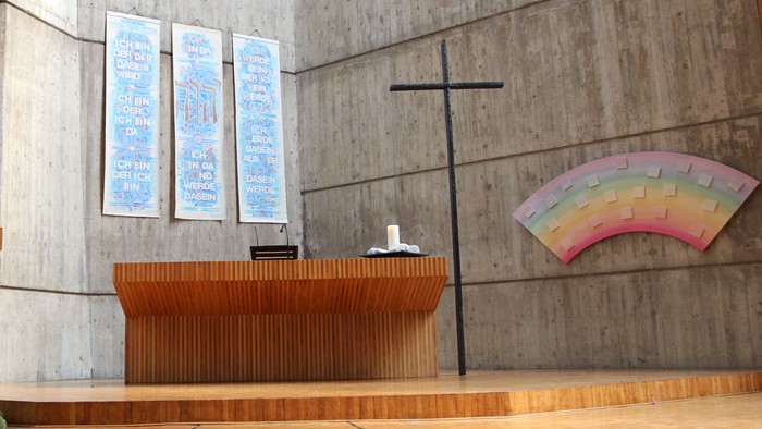 Die Kirche hat einen modernen Altar und ein farbiges Fenster.