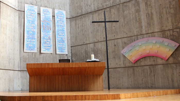 Die Kirche hat einen modernen Altar und ein farbiges Fenster.