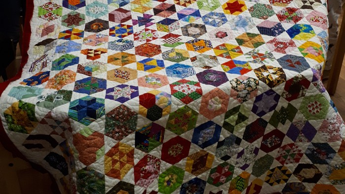 Zwei Frauen halten eine bunte Quilt-Decke hoch