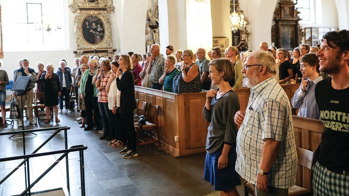 En kirkefuld med mennesker, der deltager i en gudstjeneste