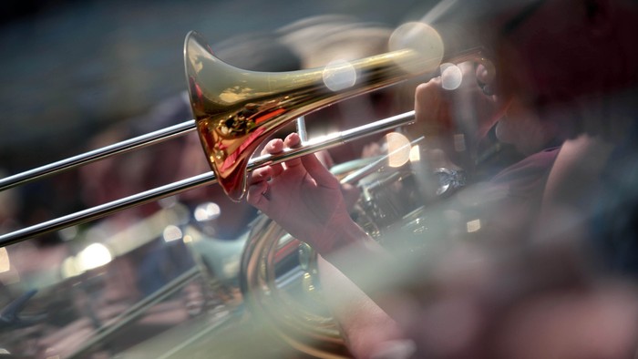 Eine Person spielt ein Blechblasinstrument, umgeben von anderen Musikern.
