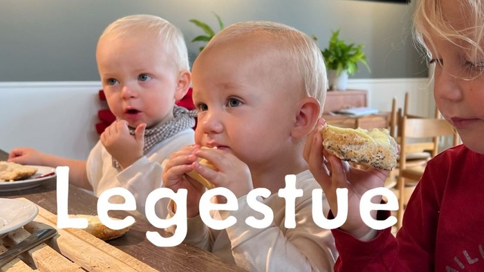 Tre små børn sidder ved bordet og spiser.