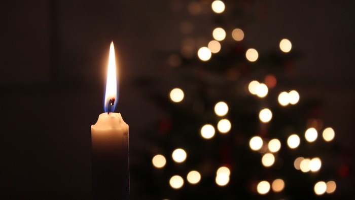 En lysende lyse med en lysende juletree i baggrunden