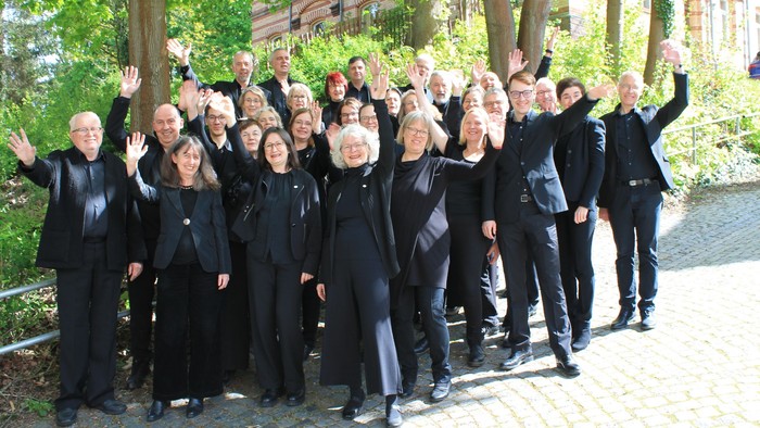 Gruppe von Personen in schwarzer Kleidung, die sich im Freien fotografieren lassen.