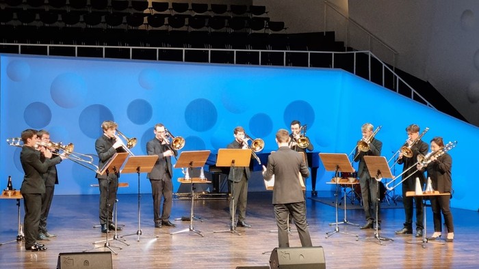 Ein Orchester probt auf einer Bühne vor blauem Hintergrund